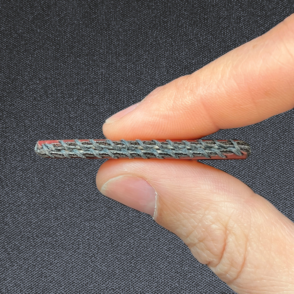 Burgundy Wildcard, held between two fingers to show its slim profile